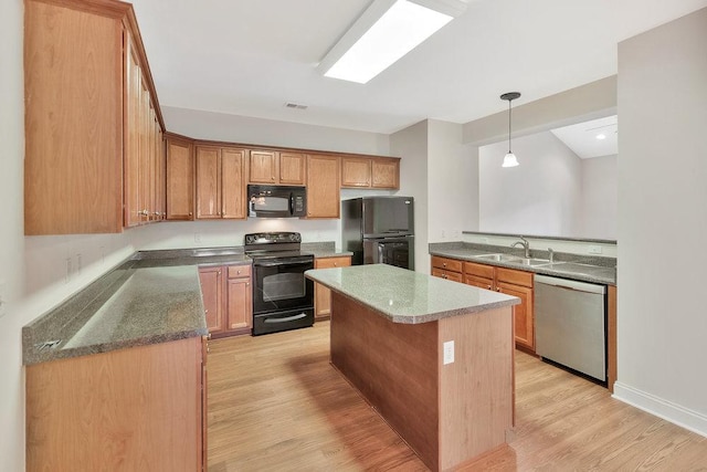 kitchen featuring a sink, light wood-style flooring, decorative light fixtures, a kitchen island, and black appliances