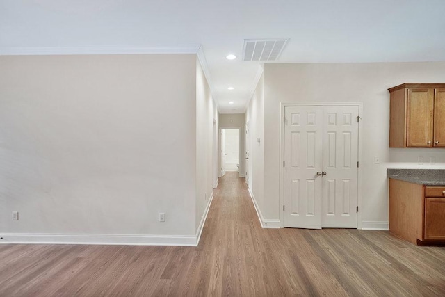 hallway featuring visible vents, crown molding, light wood-style floors, baseboards, and recessed lighting