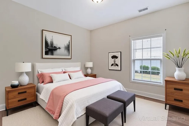 bedroom featuring baseboards, wood finished floors, and visible vents