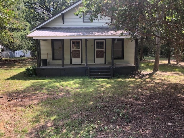 bungalow featuring covered porch, metal roof, and a front lawn