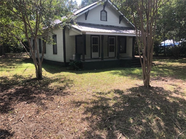 view of front facade featuring covered porch, metal roof, and a front lawn