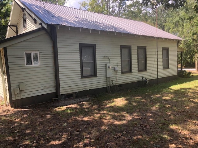 back of house with a yard, crawl space, and metal roof
