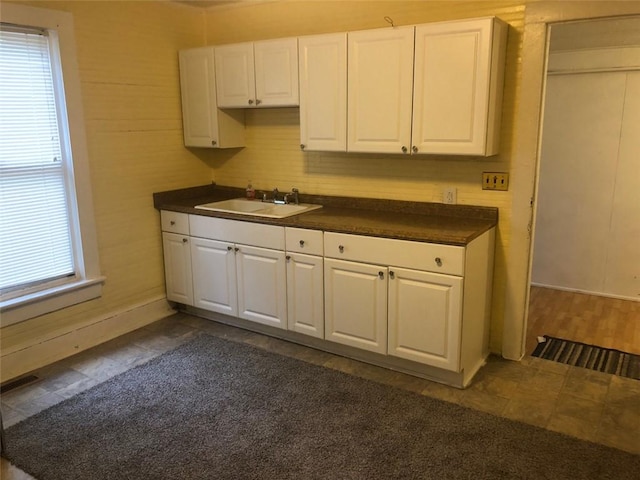 kitchen with a sink, dark countertops, white cabinets, and a wealth of natural light
