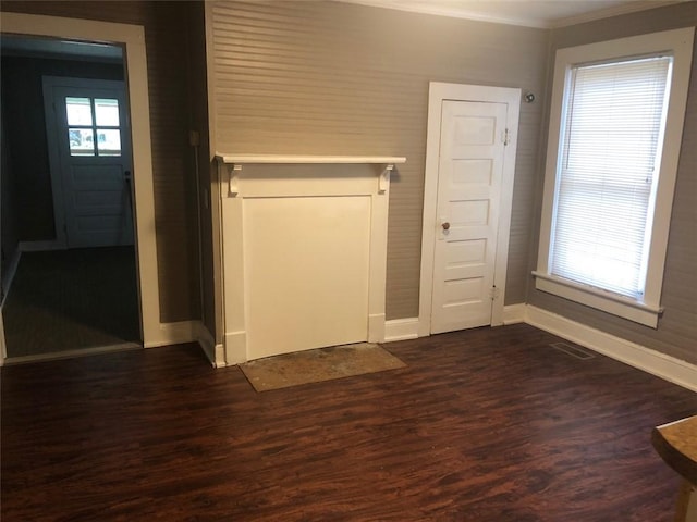 interior space featuring baseboards, ornamental molding, dark wood-type flooring, and visible vents