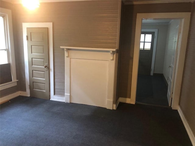 interior space featuring baseboards and dark colored carpet