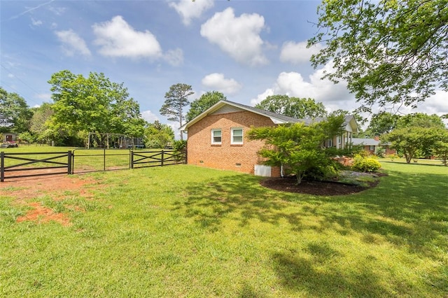 exterior space with a yard, a gate, brick siding, fence, and crawl space
