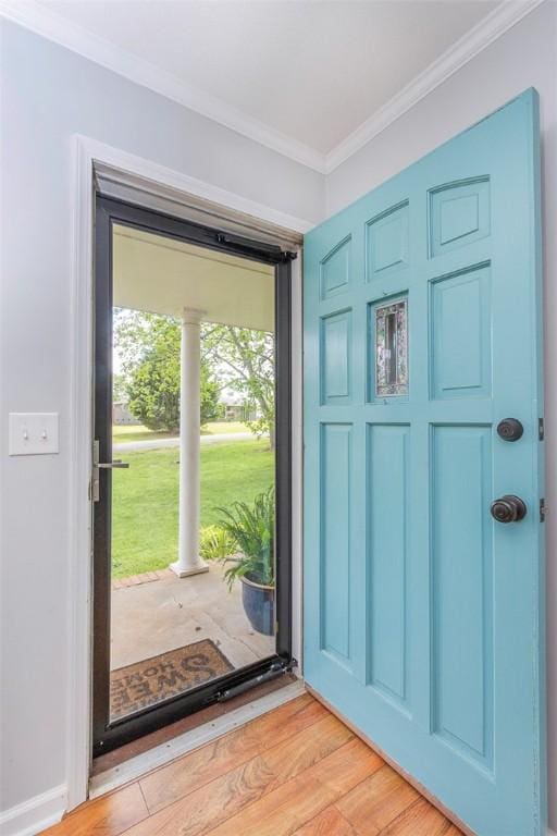 doorway with light wood-style floors and crown molding