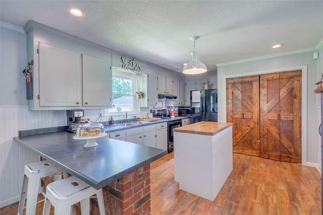 kitchen with black fridge with ice dispenser, a sink, butcher block counters, ornamental molding, and light wood finished floors