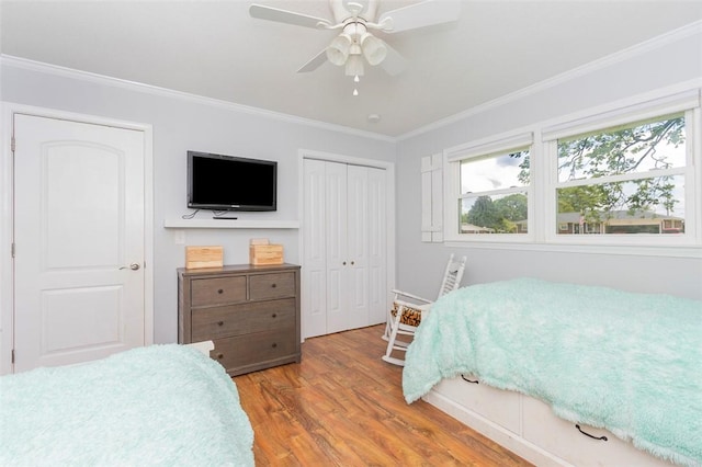bedroom with wood finished floors, a ceiling fan, a closet, and crown molding