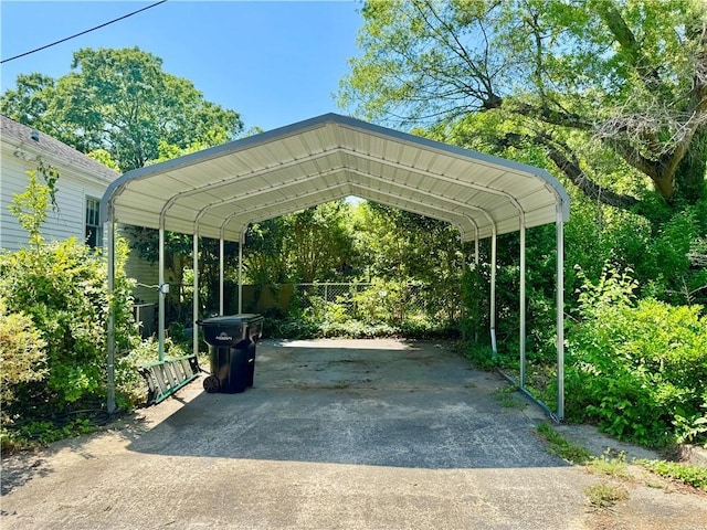 view of parking with a carport, driveway, and fence