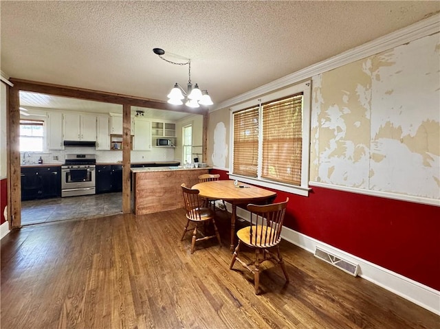 dining area featuring a textured ceiling, visible vents, a chandelier, dark wood-style flooring, and ornamental molding