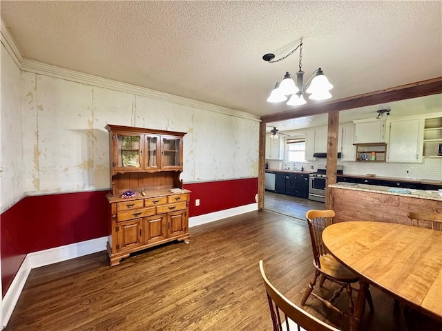 dining space featuring wood finished floors, a chandelier, ornamental molding, baseboards, and a textured ceiling