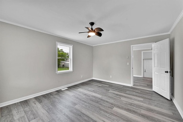 spare room with baseboards, wood finished floors, a ceiling fan, and ornamental molding