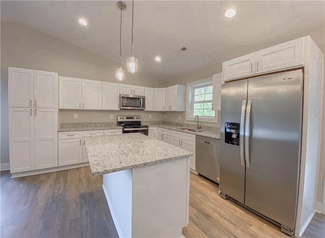 kitchen with a sink, light wood finished floors, lofted ceiling, stainless steel appliances, and white cabinetry