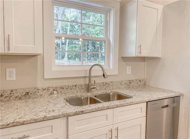 kitchen with white cabinets, light stone counters, a sink, and dishwasher