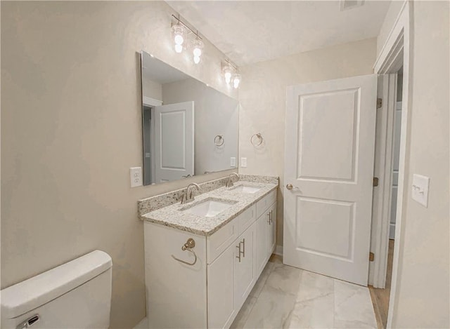 bathroom with double vanity, a sink, marble finish floor, and toilet
