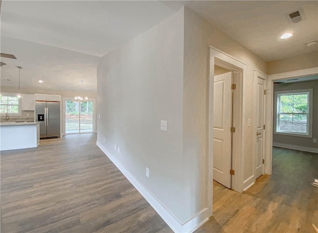 corridor featuring light wood-style floors, baseboards, and a wealth of natural light