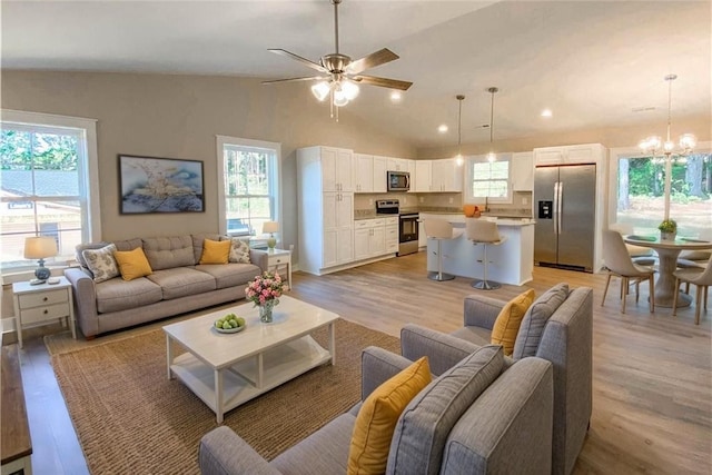 living room featuring recessed lighting, light wood-style flooring, ceiling fan with notable chandelier, and lofted ceiling