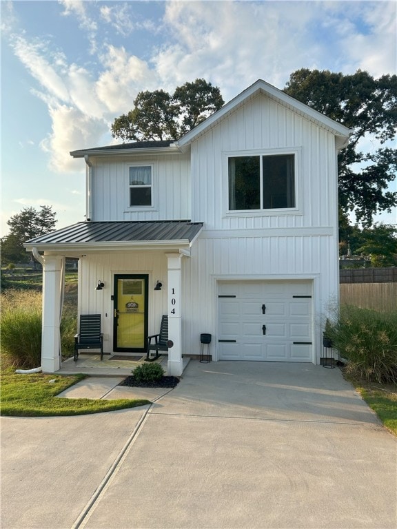modern farmhouse featuring an attached garage, concrete driveway, board and batten siding, and a standing seam roof