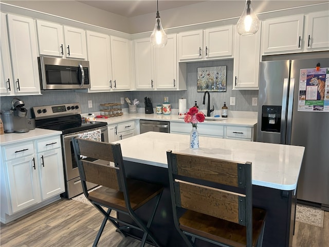 kitchen featuring a breakfast bar, light wood-style floors, white cabinets, a sink, and stainless steel appliances