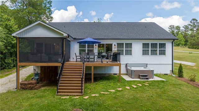 back of property with a hot tub, a sunroom, a deck, stairway, and a lawn