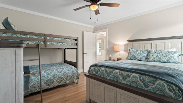 bedroom featuring ornamental molding, light wood-style flooring, and a ceiling fan