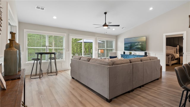 living area featuring light wood-style floors, ceiling fan, vaulted ceiling, and visible vents