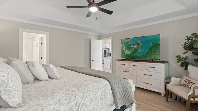 bedroom with a raised ceiling, a ceiling fan, and light wood finished floors