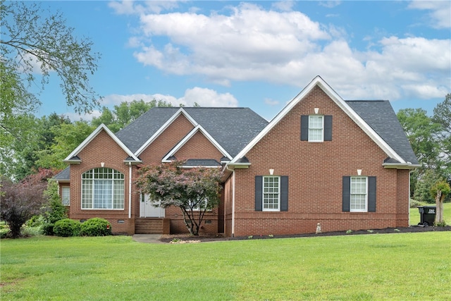 view of front of home with brick siding, a shingled roof, and a front yard