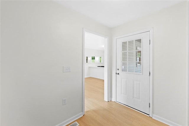 doorway with baseboards, light wood-type flooring, and visible vents