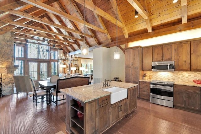kitchen featuring wood ceiling, appliances with stainless steel finishes, a sink, beamed ceiling, and an island with sink