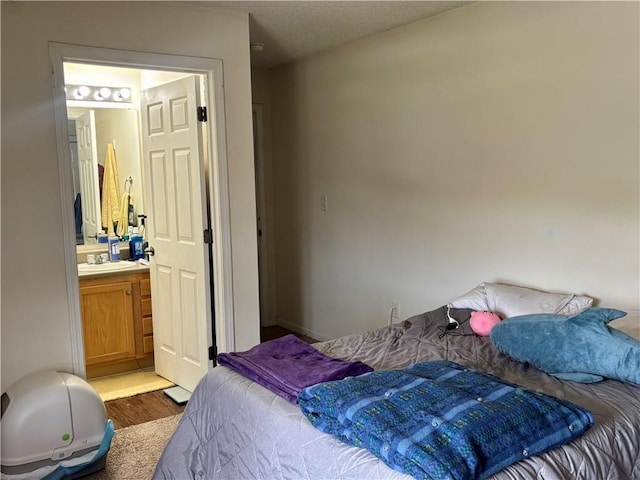 bedroom with a sink, ensuite bath, and wood finished floors