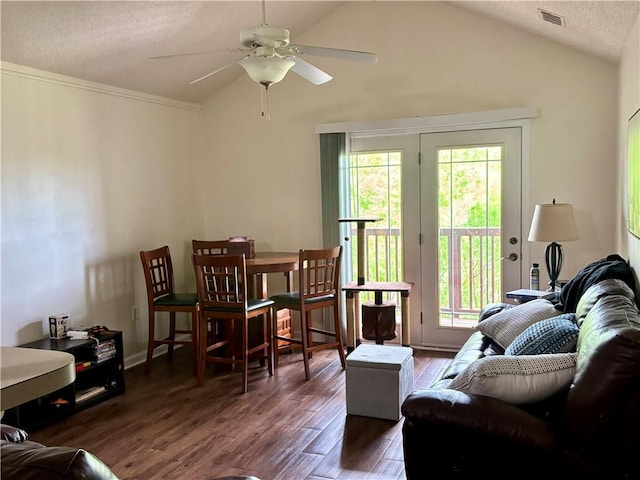 living area featuring a textured ceiling, a ceiling fan, wood finished floors, lofted ceiling, and visible vents