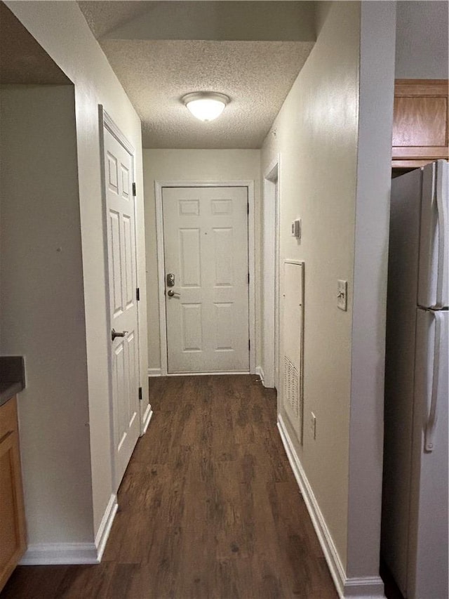 corridor with baseboards, a textured ceiling, and dark wood-style flooring