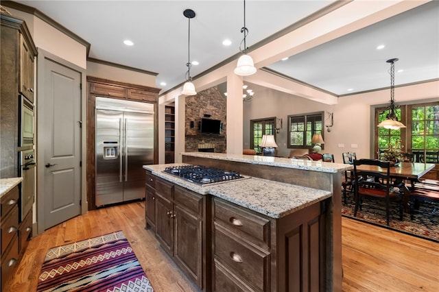 kitchen featuring built in appliances, a center island, a healthy amount of sunlight, and light wood-type flooring