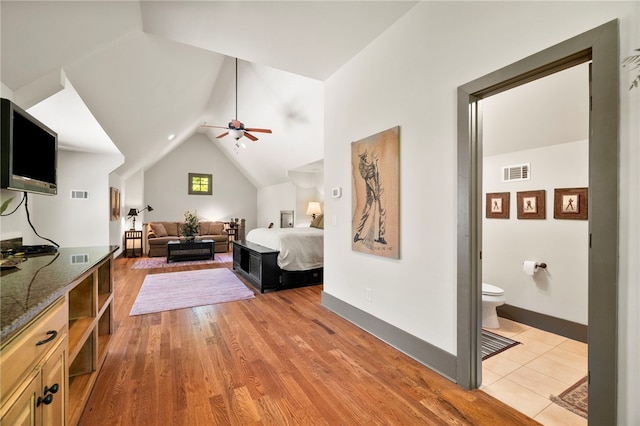 bedroom with lofted ceiling, light wood-type flooring, connected bathroom, and visible vents