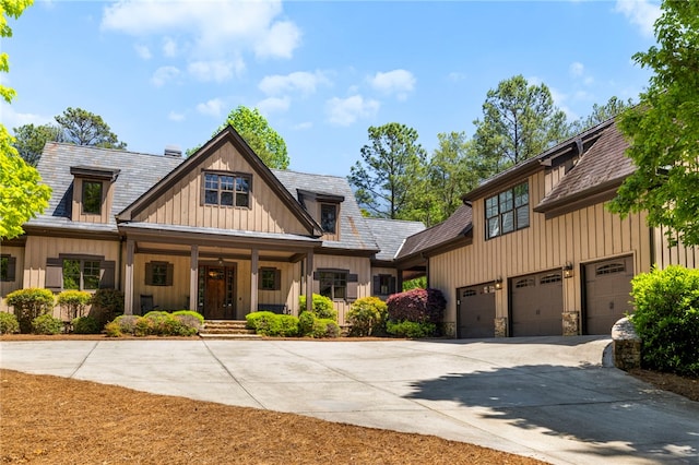 craftsman house featuring stone siding, a garage, board and batten siding, a porch, and driveway