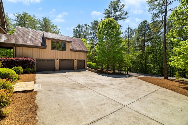 view of side of property with board and batten siding, stone siding, and concrete driveway