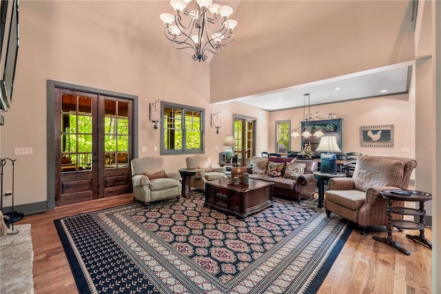 living room featuring an inviting chandelier, a high ceiling, french doors, and wood finished floors