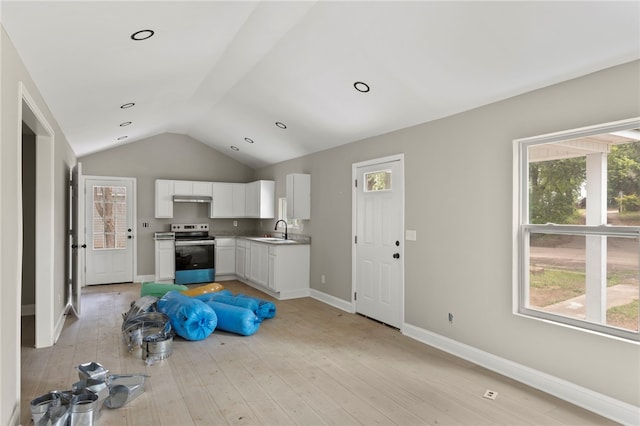 kitchen with vaulted ceiling, stainless steel range with electric stovetop, a sink, white cabinets, and light wood-style floors