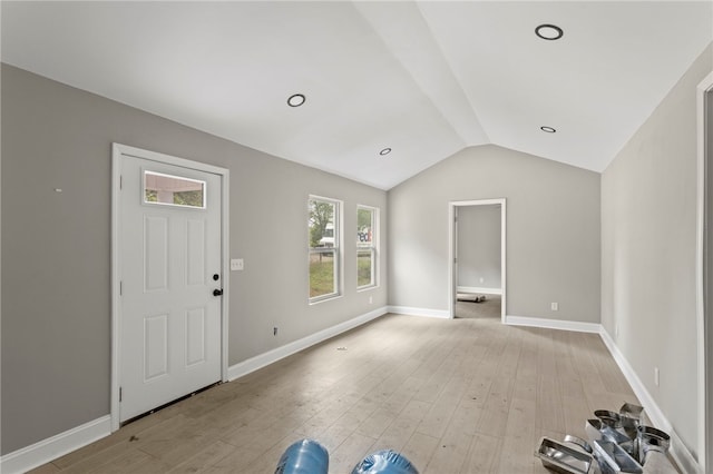 foyer entrance featuring baseboards, light wood finished floors, and lofted ceiling