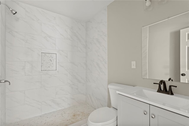 bathroom with vanity, toilet, and tiled shower