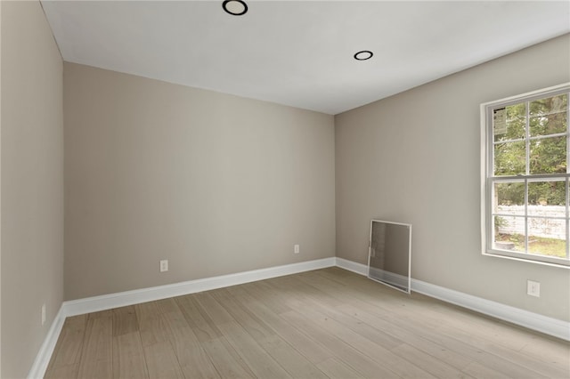 empty room featuring baseboards, plenty of natural light, and light wood-type flooring