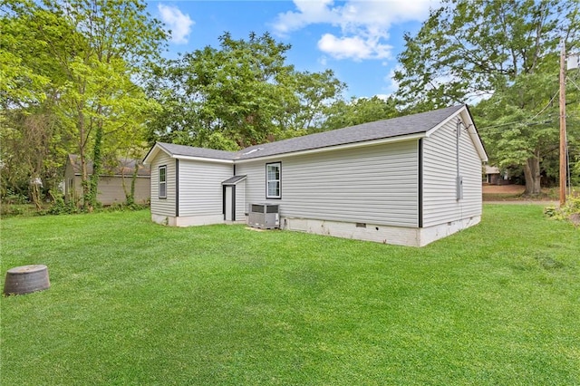 rear view of house featuring central air condition unit, crawl space, a shingled roof, and a lawn