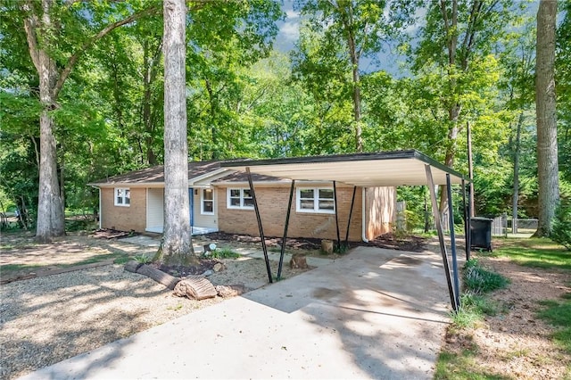 single story home featuring brick siding, a carport, and concrete driveway