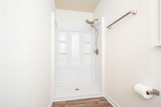 full bathroom featuring baseboards, a shower stall, and wood finished floors