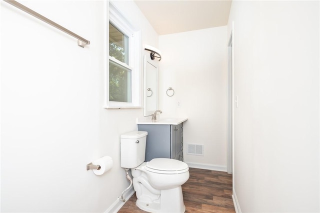 bathroom featuring visible vents, vanity, wood finished floors, toilet, and baseboards