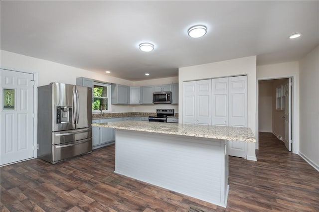 kitchen featuring appliances with stainless steel finishes, gray cabinets, a center island, and dark wood finished floors