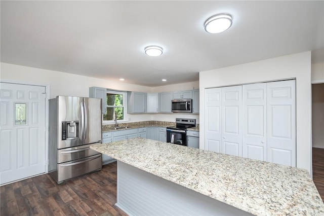 kitchen featuring dark wood-style flooring, a sink, gray cabinets, and appliances with stainless steel finishes