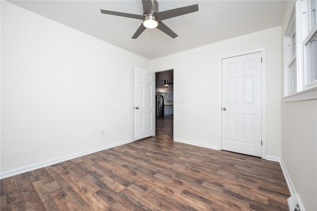 unfurnished bedroom with a ceiling fan, baseboards, and dark wood-style floors